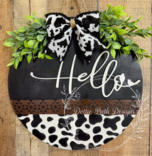 Load image into Gallery viewer, Farmhouse Hello Door Hanger – 16” Black & White Cow Print with Greenery and Bow – Rustic Wooden Front Door Sign