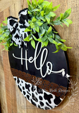 Load image into Gallery viewer, Farmhouse Hello Door Hanger – 16” Black & White Cow Print with Greenery and Bow – Rustic Wooden Front Door Sign